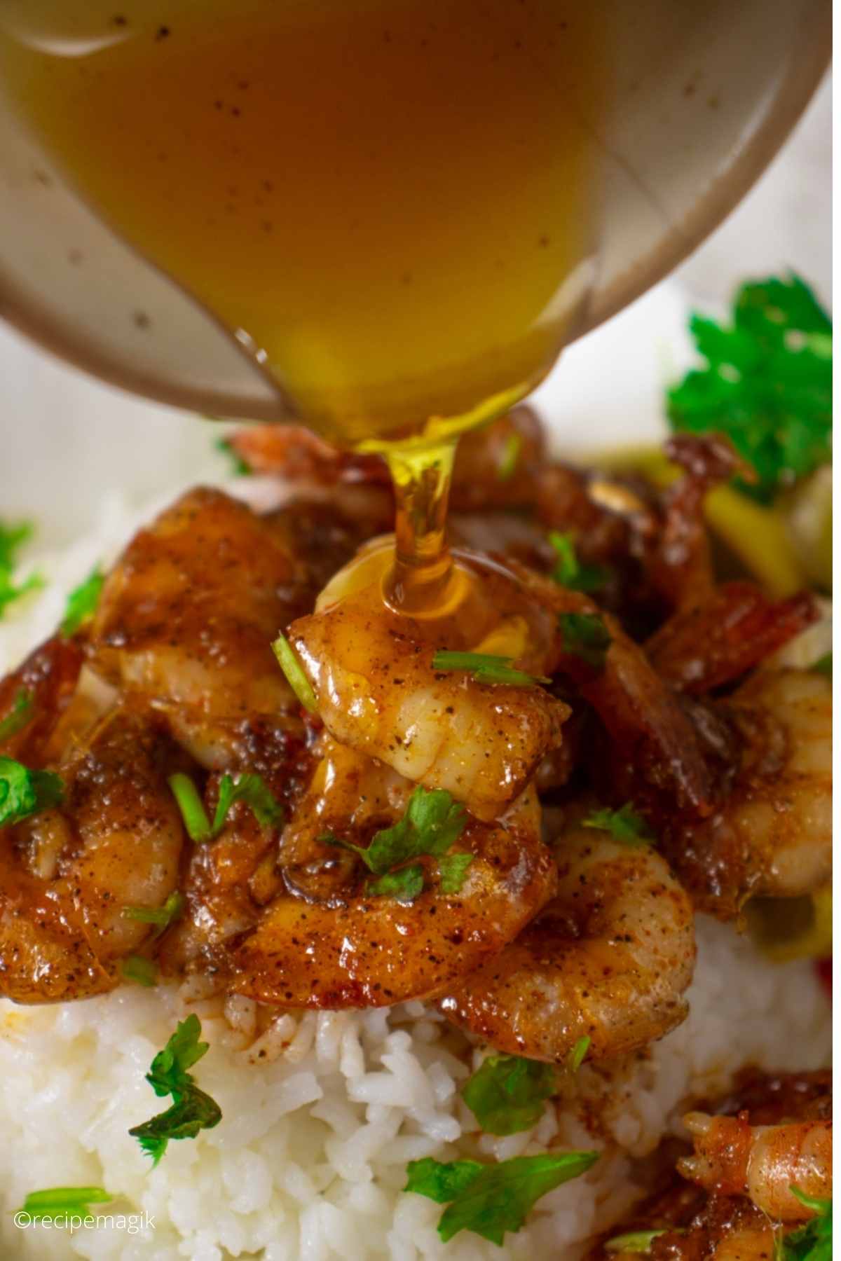pouring honey on shrimps over rice garnished with parsley