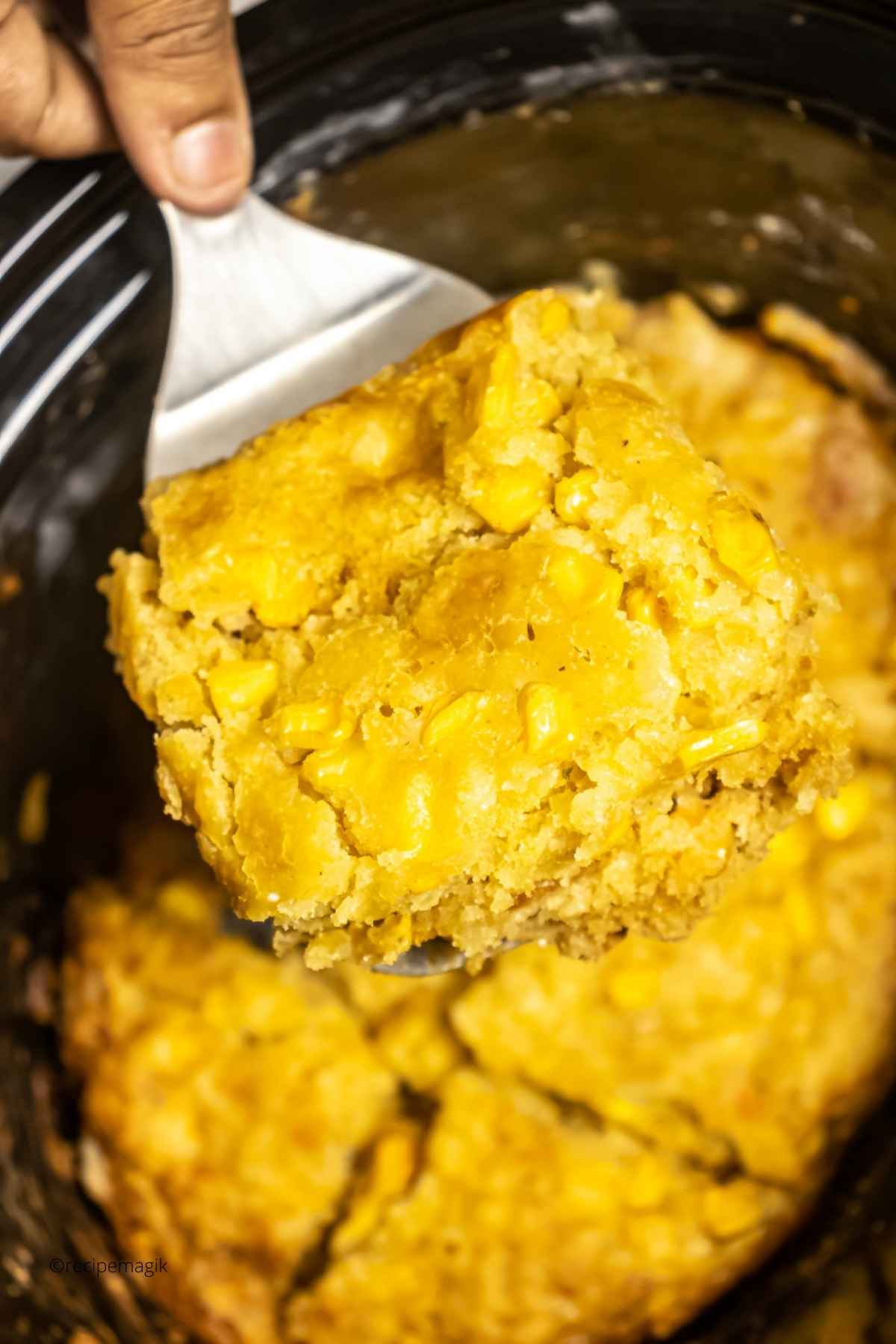 scooping out corn casserole from slow cooker