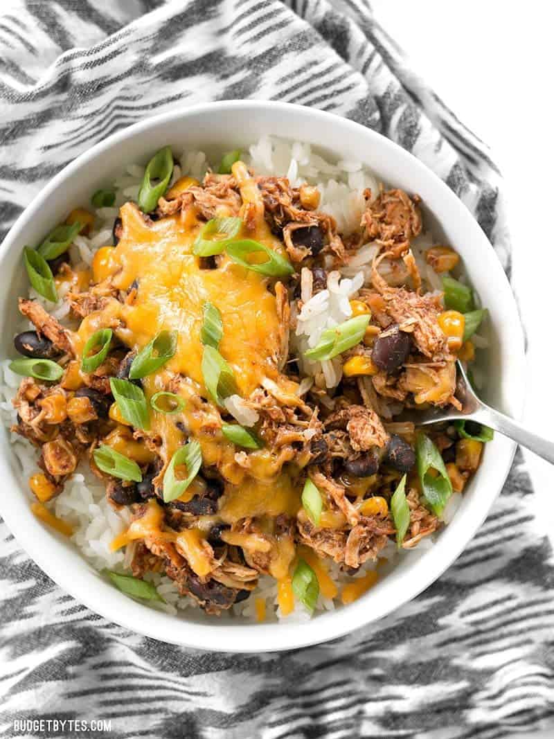 taco chicken bowl with green onions and melted cheddar cheese in a white bowl