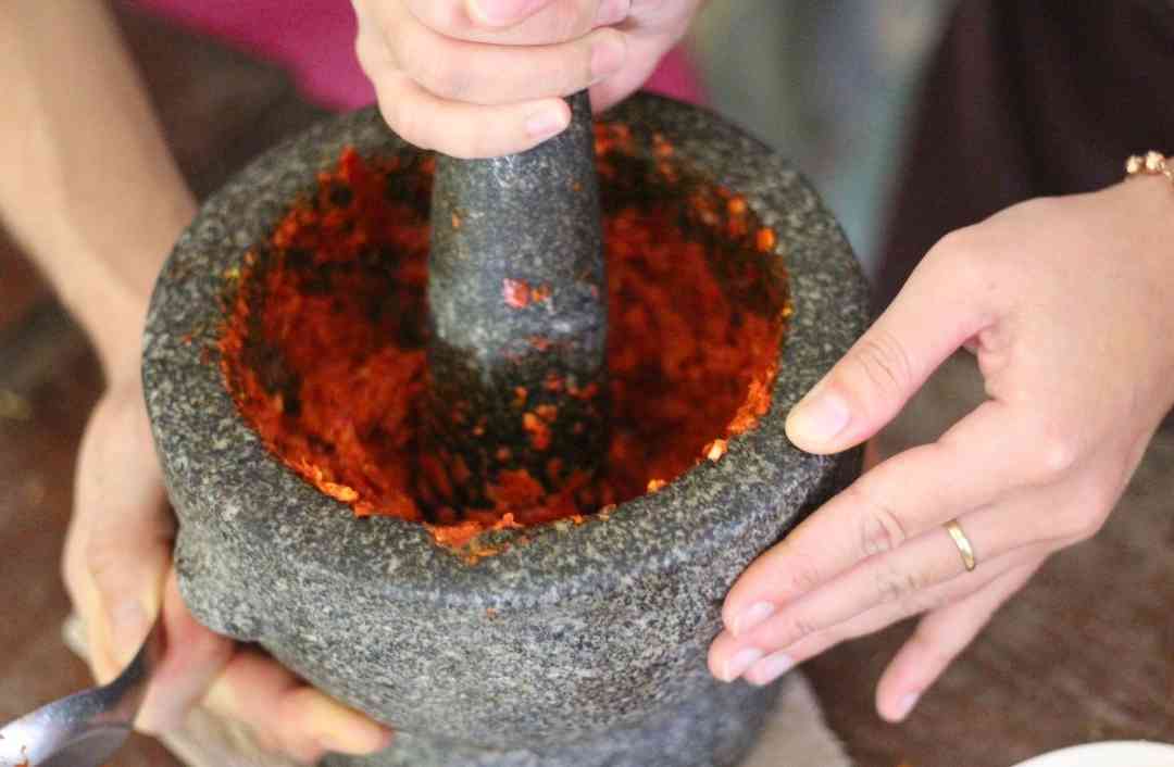 making thai red curry paste in a mortar pestle in a traditional way