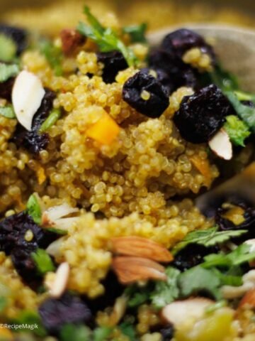 closeup of quinoa pilaf in a spatula with parsley almonds and cranberries