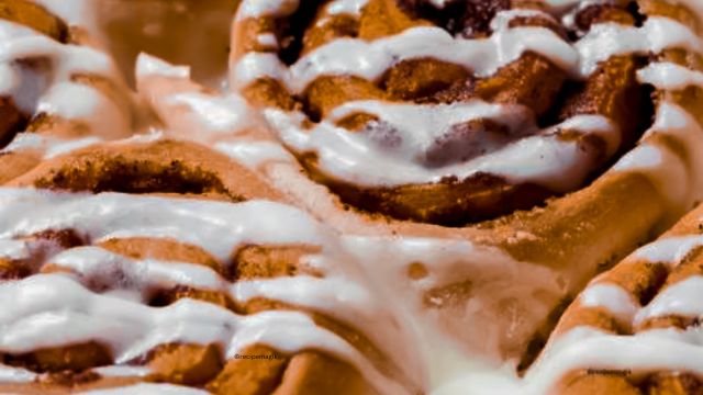 close view of gingerbread cinnamon roll drizzled with cinnamon cream cheese frosting on top