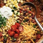 summer chili in a dutch pot oven with sour cream, zucchini and tomatoes on top