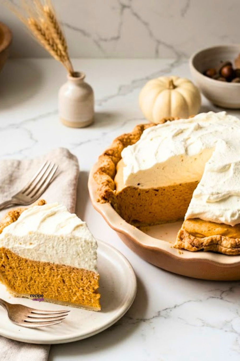 Whole creamy pumpkin chiffon pie dusted with cinnamon on a rustic fall table setting